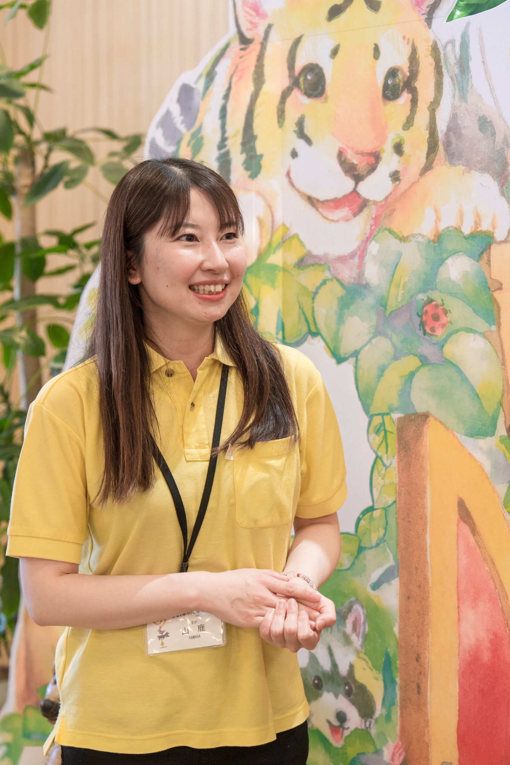 照葉スパリゾート門司店×到津の森公園コラボのフォトスポット前で笑顔を見せる到津の森公園スタッフの山鹿さん。
