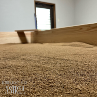 北九州市八幡西区の酵素風呂ASTREA（アストレア）にて、米ぬかを丁寧に整えるスタッフの様子。清潔感のある店内で、ふかふかの米ぬか酵素風呂を提供しています。