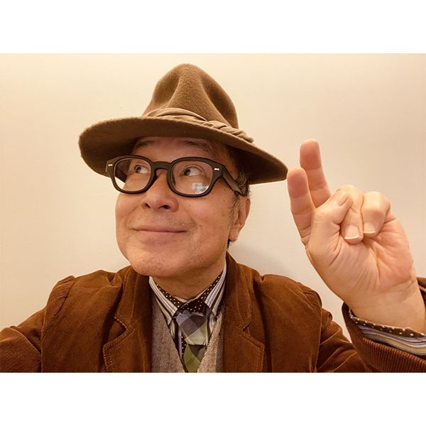 ハットをかぶり、柔らかな笑顔で上を見つめるジャズピアニストの大江千里。人差し指を立てたポーズは、ポップスとジャズが融合した“三代目”としての新たな表現への意欲と、今回のツアーテーマ「ふたつの宿題」への真摯な向き合い方を感じさせる。