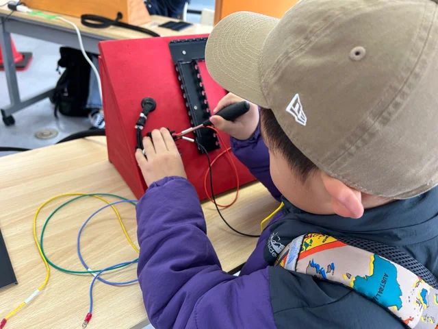 本物のドライバーを使い、ライトを点灯させるための配線作業に挑戦する子どもの様子